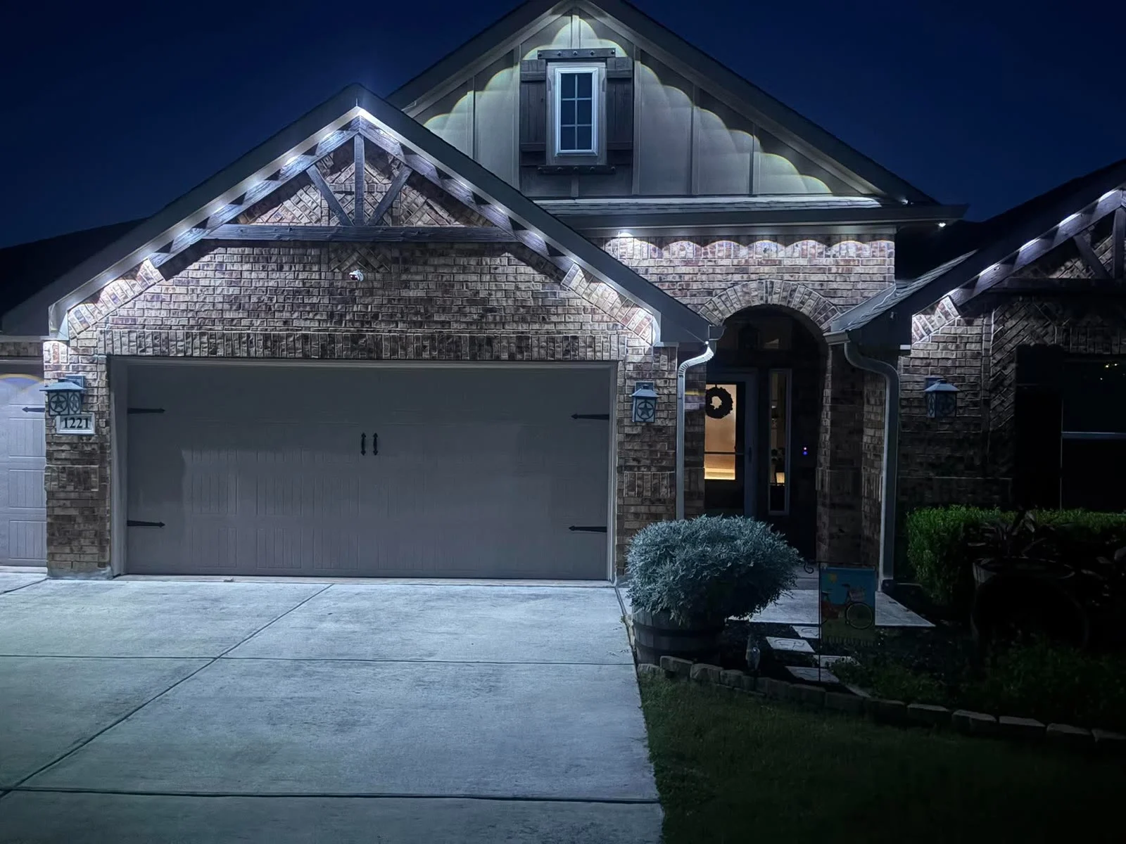 Real Skyclear install — warm-white permanent roofline lighting on a brick home at night